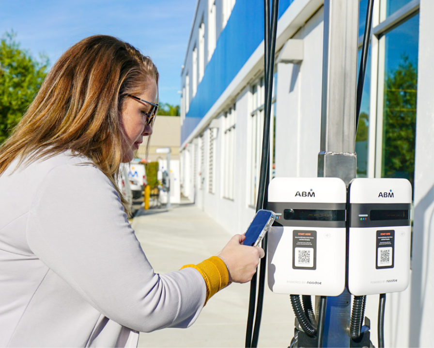 Close-up photo of a customer using her mobile device to scan the QR code on an EV charger.