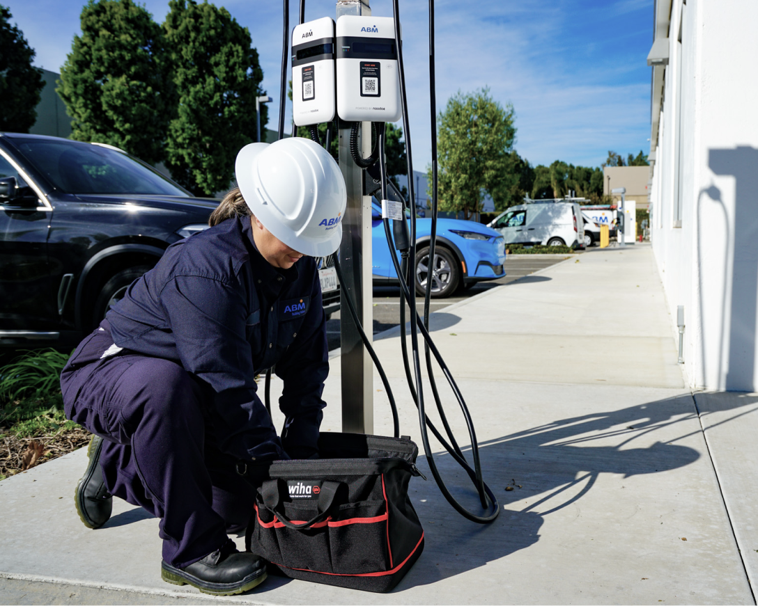 Photo of a female ABM technician installing an EV charger.