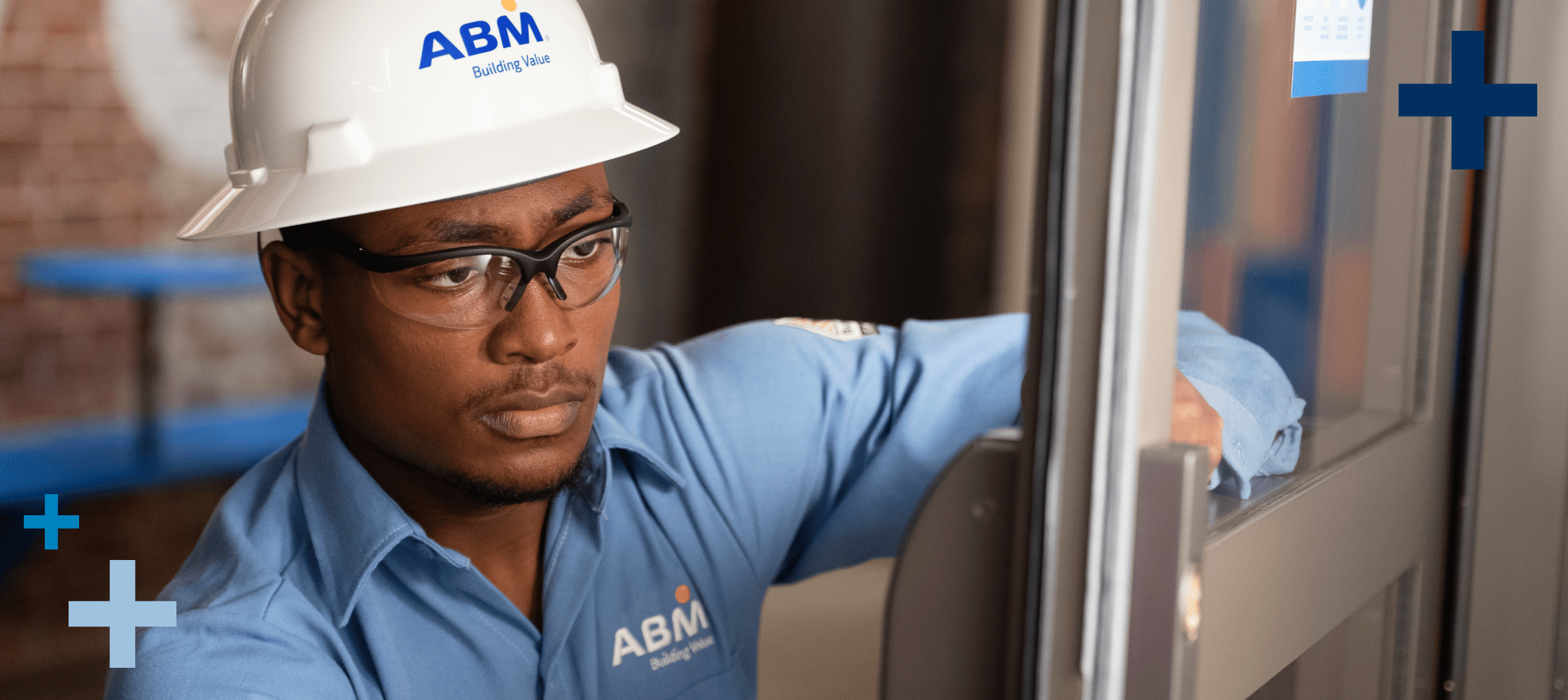 Male ABM engineer wearing a blue shirt and white hard hat inspecting a hotel door