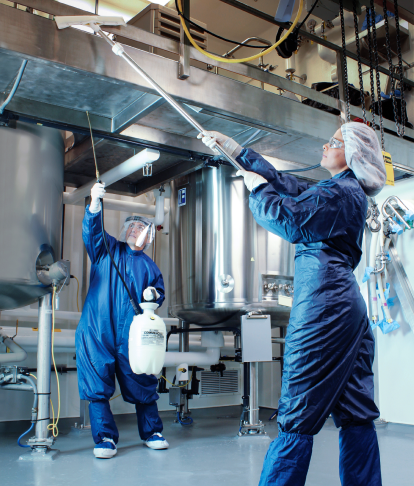 Two people in overalls sanitizing equipment