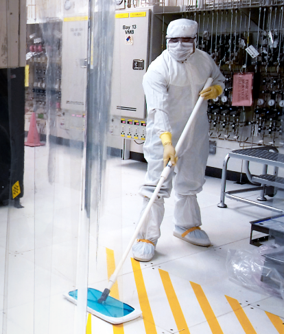 A person in white overalls cleaning a Life Sciences space