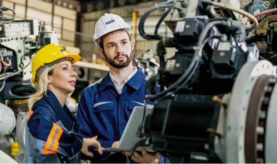 Two people in hardhats looking at an engine